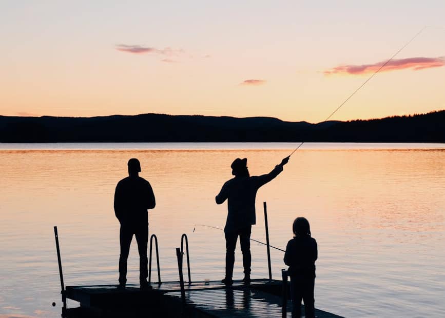 three people on a wooden fishing docks